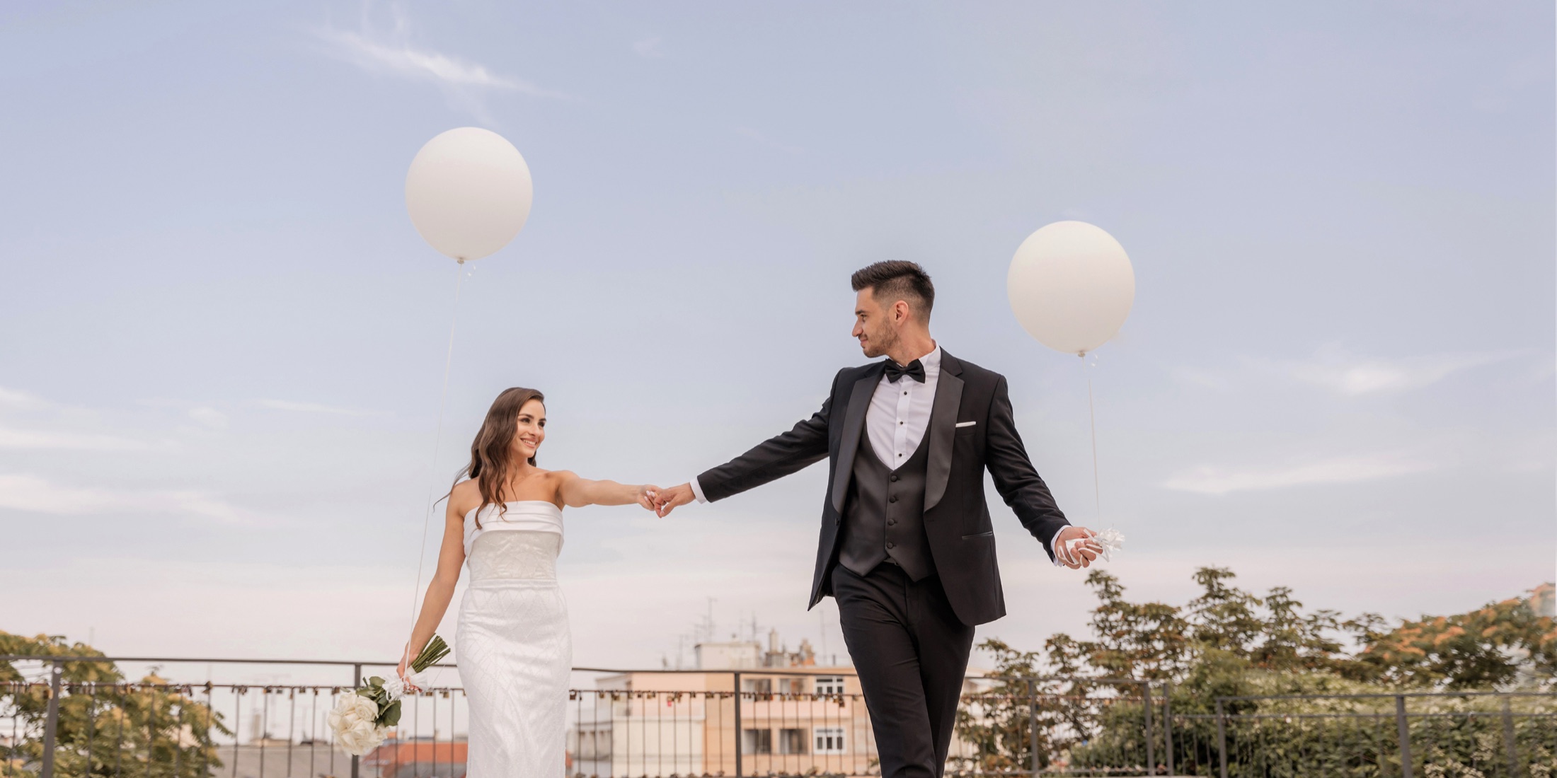 Mladenci drže se za ruke na jezeru okruženom balonima